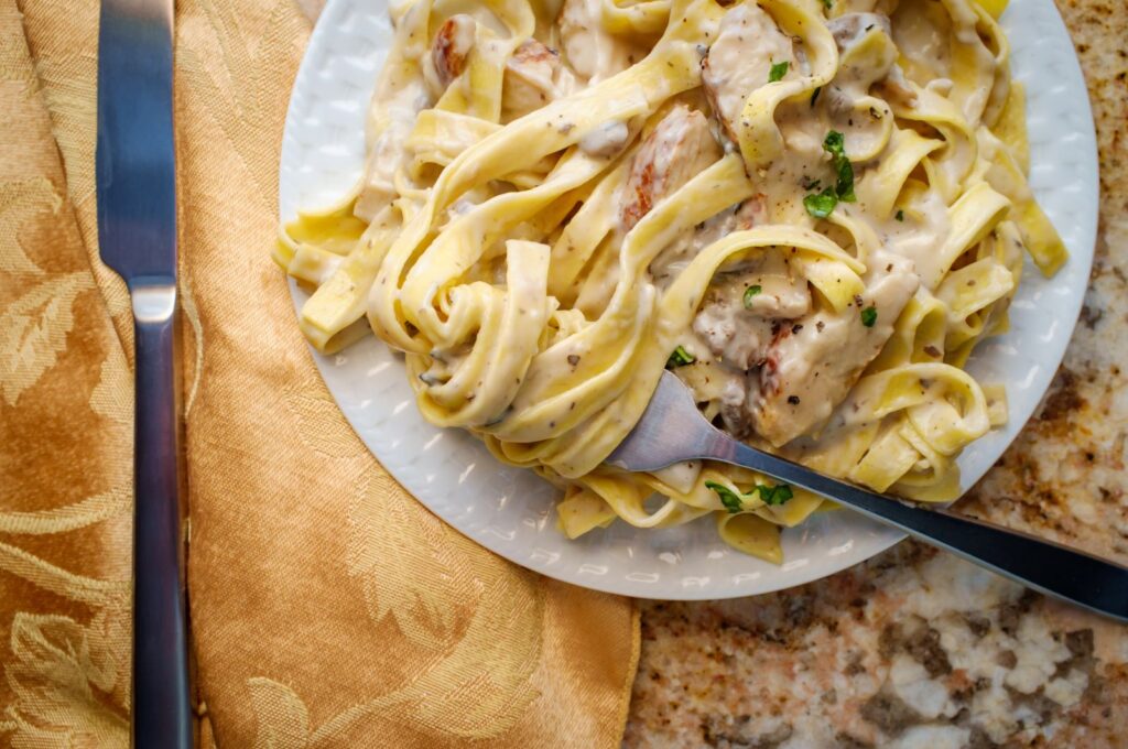 Creamy chicken Alfredo with green seasoning, fettuccine and sliced pan-seared chicken