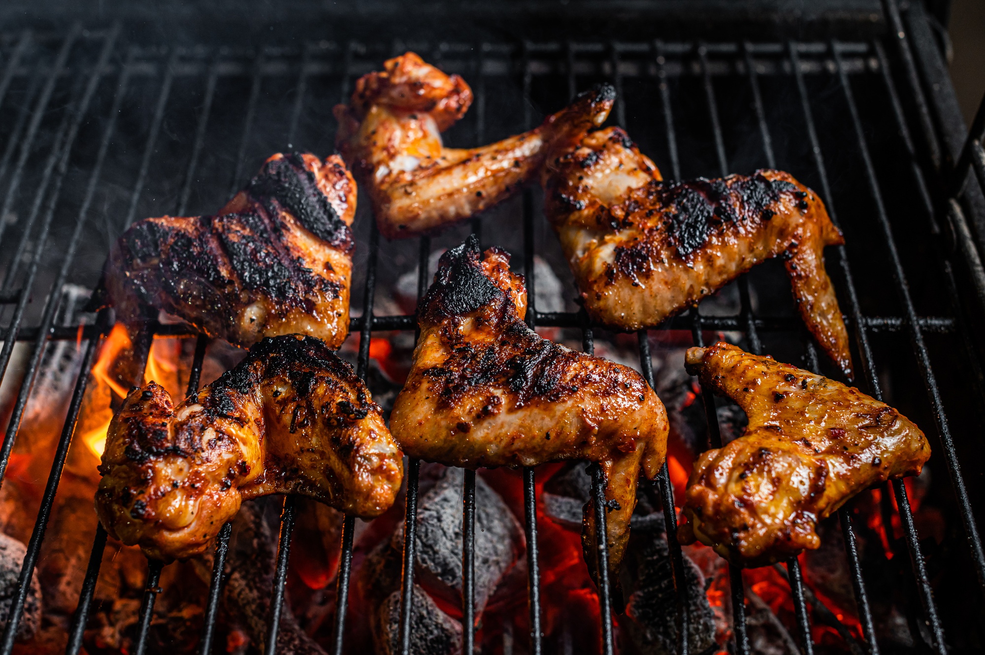 Chicken wings on barbecue, outdoor BBQ grill with fire. Top view