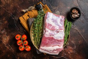 Farm fresh Pork belly, raw meat in a plate with spices. Dark background. Top view